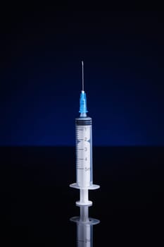 Syringe with needle, upright standing, isolated with background light