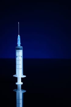 Syringe, isolated on black and blue background