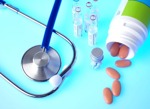 Medicine in bottle on blue background, with stethoscope
