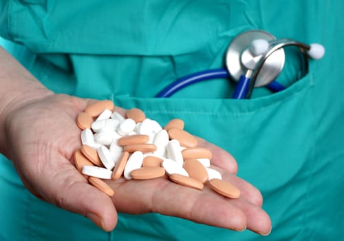 Nurse holding prescription medicine in hospital gown