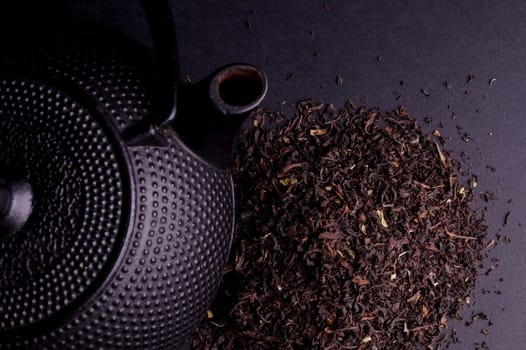 Black Teapot with Healthy Tea Leaves Isolated on Black