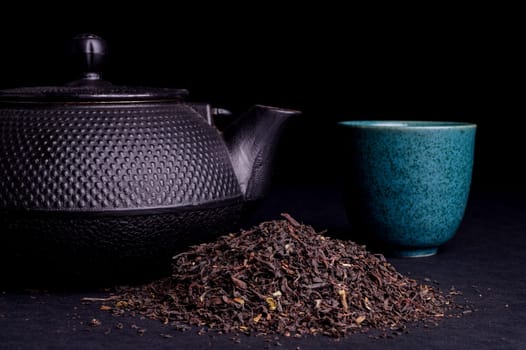 Black Teapot with Healthy Tea Leaves Isolated on Black