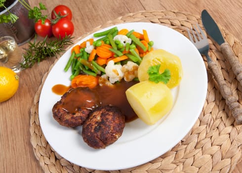fried meatballs on a plate of vegetables and potatoes