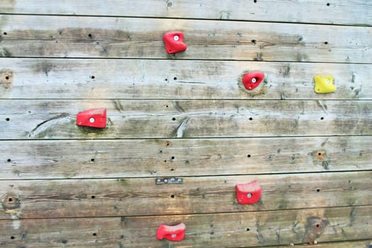 wooden climbing wall with bright colored foot holds