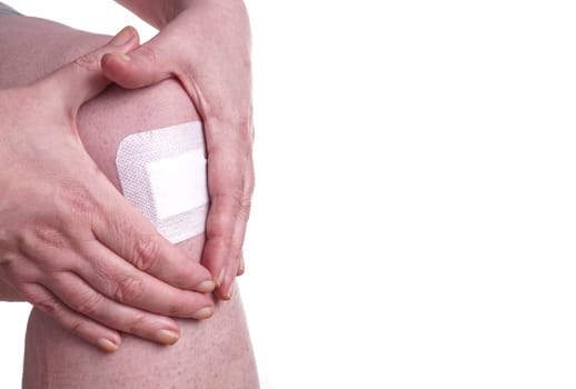 Women with wounds on her knees. The damage is treated with an adhesive bandage , so to prevent the blood from flowing. Isolated on white