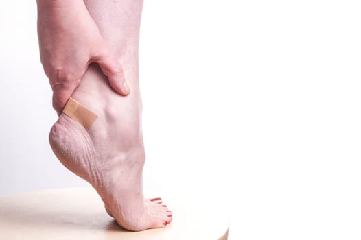 Women with wounds on her ankle . The injury came after she had new shoes on and treated with a patch to prevent the blood flowing . Isolated on white