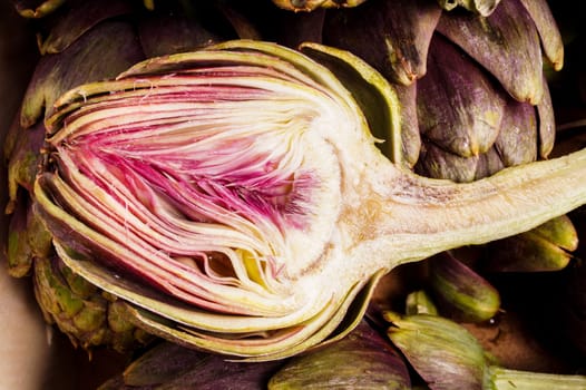 Pile of Purple artichokes ready for cooking. One artichoke is cut