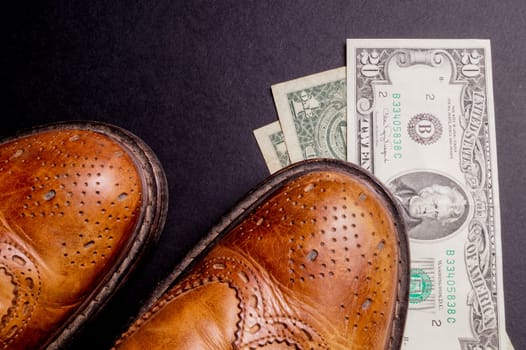 Dollars under a pair of Shoes. Business and Money or the cost of a Date. Isolated on Black