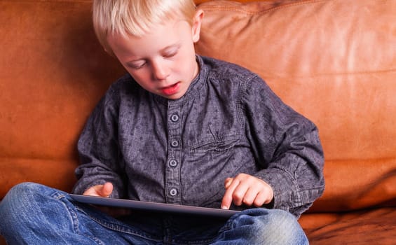 Child with Digital tablet. The Boy play and learn when he is using the tablet