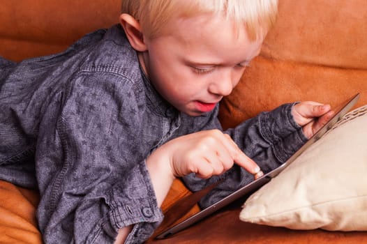 Child with Digital tablet. The Boy play and learn when he is using the tablet
