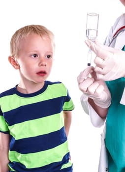 doctor or nurse preparing injection of little boy. The child looks nervous while clear liquid pulls into the syringe. The little boy must be vaccinated or given medicine against a disease