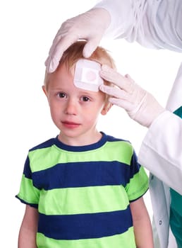 Child gets injury on the forehead and the nurse helps with getting plaster on the wound so it can heal