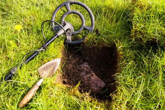 Metal Detector. Beside the detector lies a trowel ready to dig the treasure out of the ground