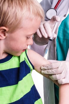 little boy given an injection by the family doctor. The female doctor gives the child an injection in the upper arm. It can be both a vaccination or as part of the boy's medical treatment