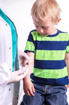 The child has a blood test . The blood sample taken by a lab technician or doctor . The boy is very brave and sit quietly while the sample taken