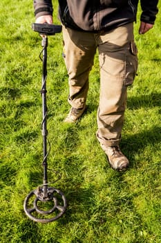 Metal Detector. Man with metal detector , he uses it to find archaeological treasures in the grass