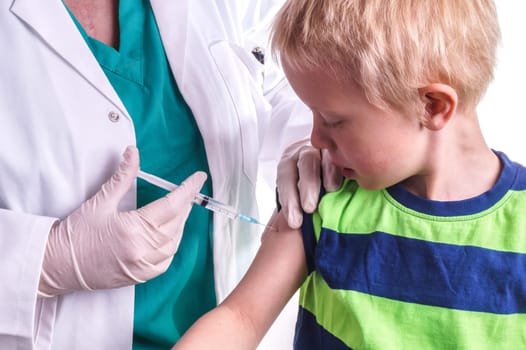 little boy given an injection by the family doctor. The female doctor gives the child an injection in the upper arm. It can be both a vaccination or as part of the boy's medical treatment