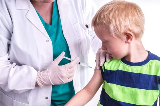 little boy given an injection by the family doctor. The female doctor gives the child an injection in the upper arm. It can be both a vaccination or as part of the boy's medical treatment