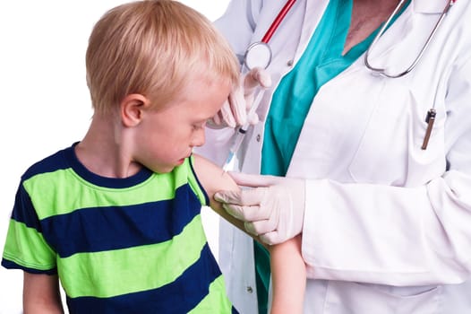 little boy given an injection by the family doctor. The female doctor gives the child an injection in the upper arm. It can be both a vaccination or as part of the boy's medical treatment