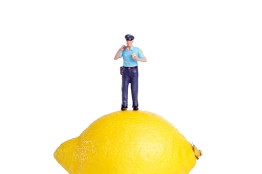 small figure of a Policeman standing on an Lemon, isolated on white