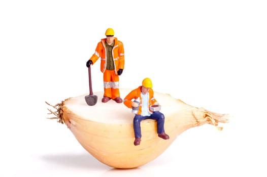small figure of workers standing and sitting on half an onion, isolated on white