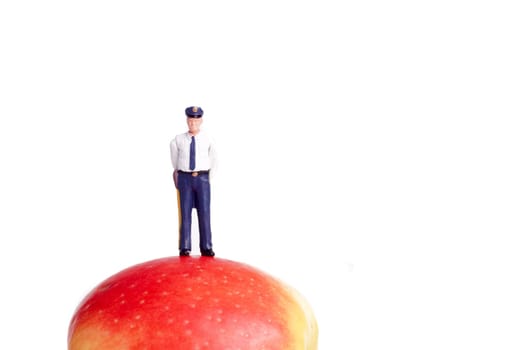small figure of a Policeman standing on an Apple, isolated on white