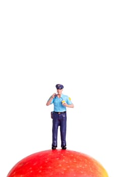 small figure of a Policeman standing on an Apple, isolated on white