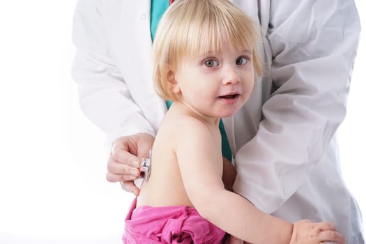 The doctor examines toddler child and listening to heart and lungs with stethoscope. The baby girl is happy, isolated on white