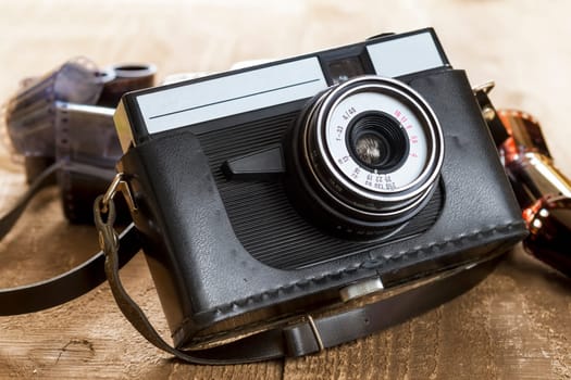 old camera and blank film strip on wooden table