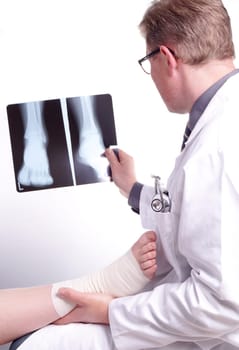 The doctor examines an X-ray picture , while the patient&#39 s sprained foot resting in his hand