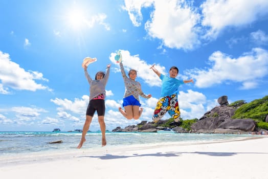 Family travels on vacation jumping with happy on beach near the sea under the sun blue sky and clouds of summer at Koh Similan Island in Mu Ko Similan National Park, Phang Nga province, Thailand