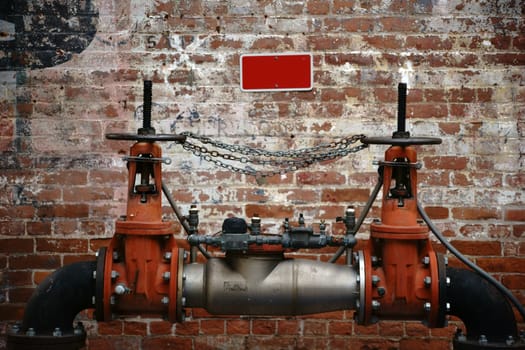 A pumping station stands in front of an old brick wall with faded characters and layers of paint.