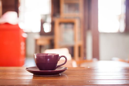 Purple coffee cup on wooden table in coffee shop