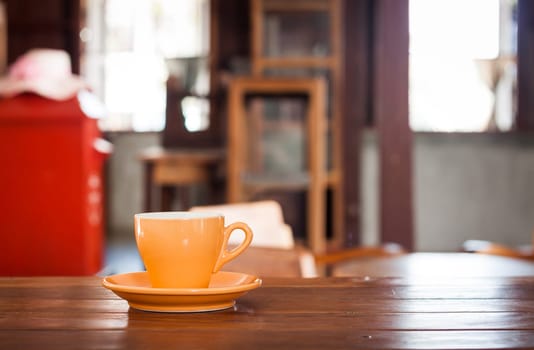 Orange coffee cup on wooden table in coffee shop