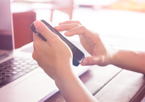 Woman using smart phone and laptop on work station