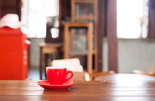 Red coffee cup on wooden table in coffee shop
