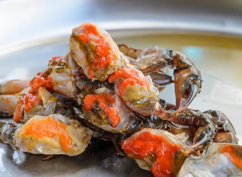 Fresh raw female crab marinated in fish sauce on stainless steel serving tray. Thai street food.