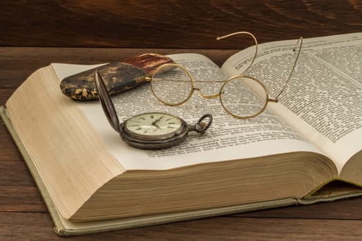 old book with glasses and pocket watch