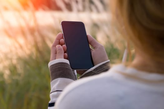 woman holding smartphone during sunset