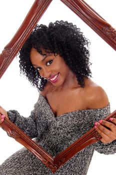 A beautiful smiling African American women holding a picture frame and.looking trough, in gray sweater, isolated for white background..