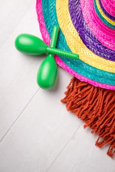 Mexican sombrero, blanket and pair of maracas on wood background.