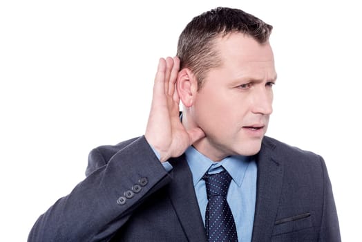Curious businessman keeping his hand near ear