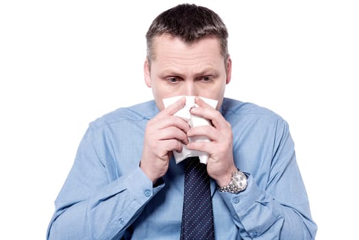 Sick businessman blowing his nose into a tissue