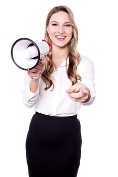 Happy young woman holding bullhorn and pointing towards camera