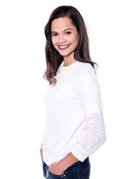 Side pose of smiling young woman with hands in pockets