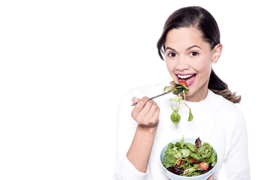 Happy young female model eating green salad