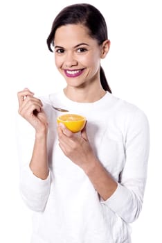 Woman eating an orange, using spoon.