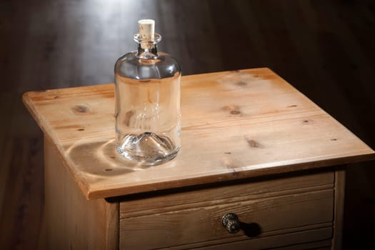 Empty bottle on a vintage wooden table with closed drawer