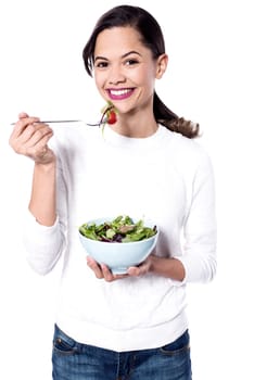 Healthy young woman eating green salad over white