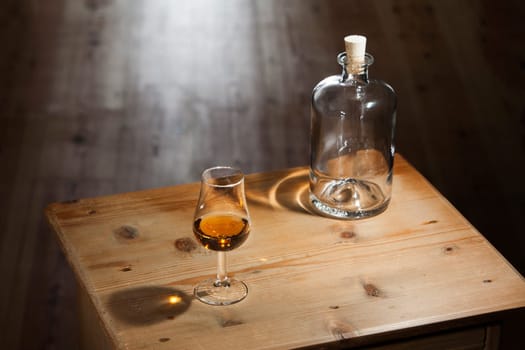 Empty bottle and a glass of brandy on an vintage wooden table
